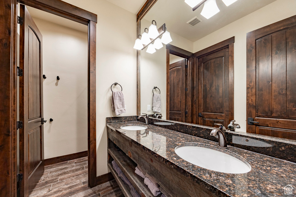 Full bath featuring a sink, double vanity, visible vents, and wood finished floors