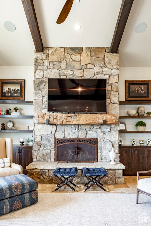 Living room with a fireplace, a ceiling fan, and beamed ceiling