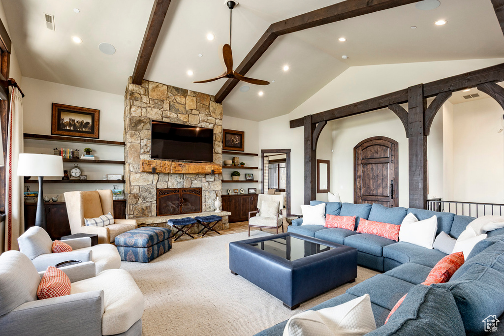 Living area with a stone fireplace, ceiling fan, visible vents, arched walkways, and beam ceiling