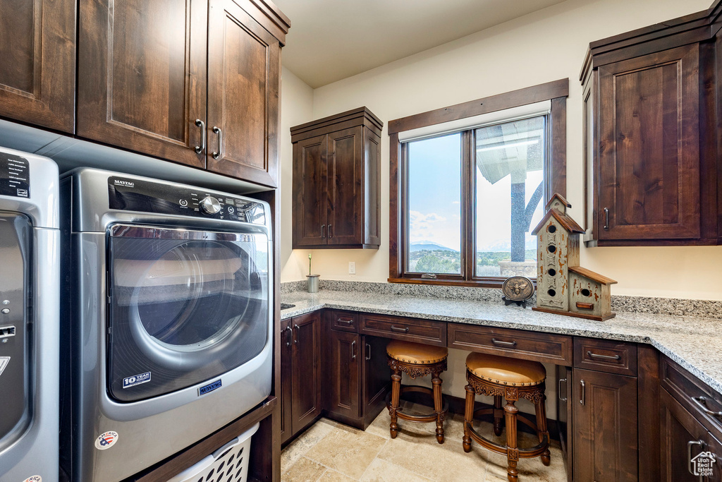 Clothes washing area featuring cabinet space and stone finish flooring
