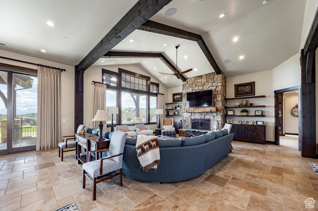 Living area with beamed ceiling, a fireplace, high vaulted ceiling, and stone tile flooring
