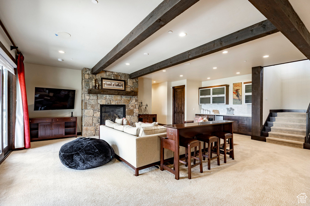 Living room with recessed lighting, beam ceiling, a stone fireplace, light colored carpet, and stairs
