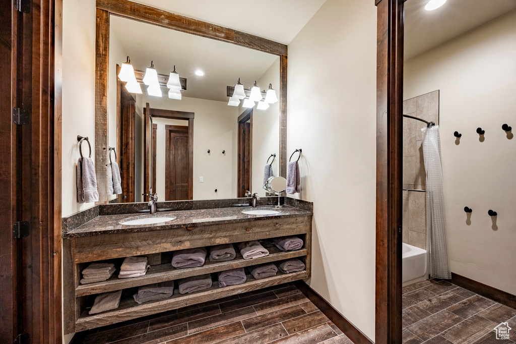 Bathroom featuring shower / tub combo, double vanity, a sink, and wood finished floors