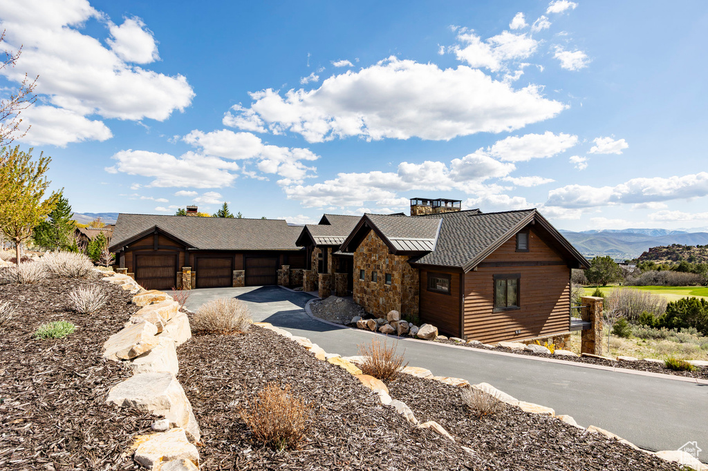View of front facade featuring stone siding, a mountain view, an attached garage, metal roof, and a standing seam roof