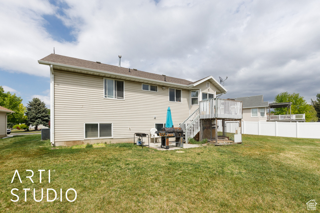 Rear view of property featuring a lawn, fence, a patio area, stairway, and a wooden deck
