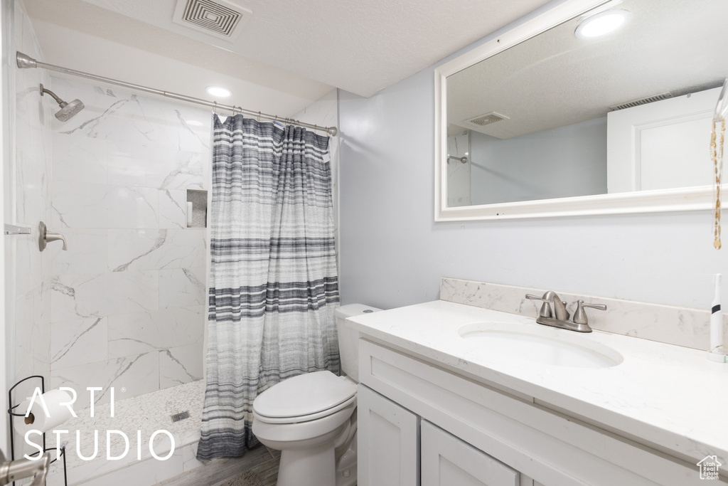 Full bathroom with toilet, vanity, visible vents, and curtained shower