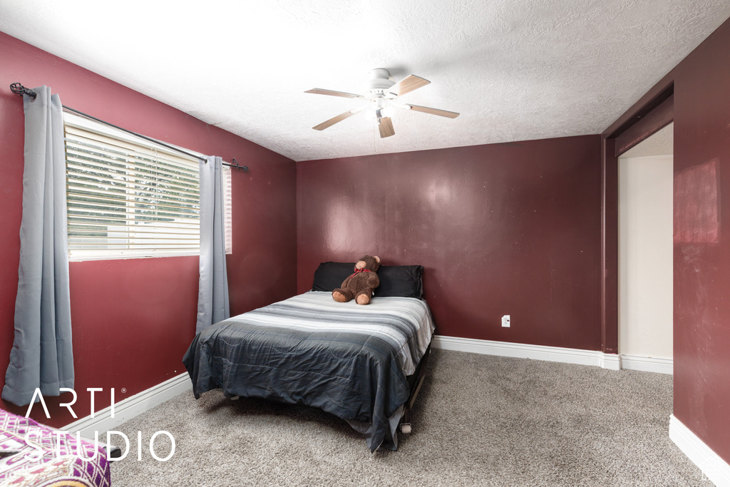 Bedroom featuring carpet, a textured ceiling, baseboards, and a ceiling fan