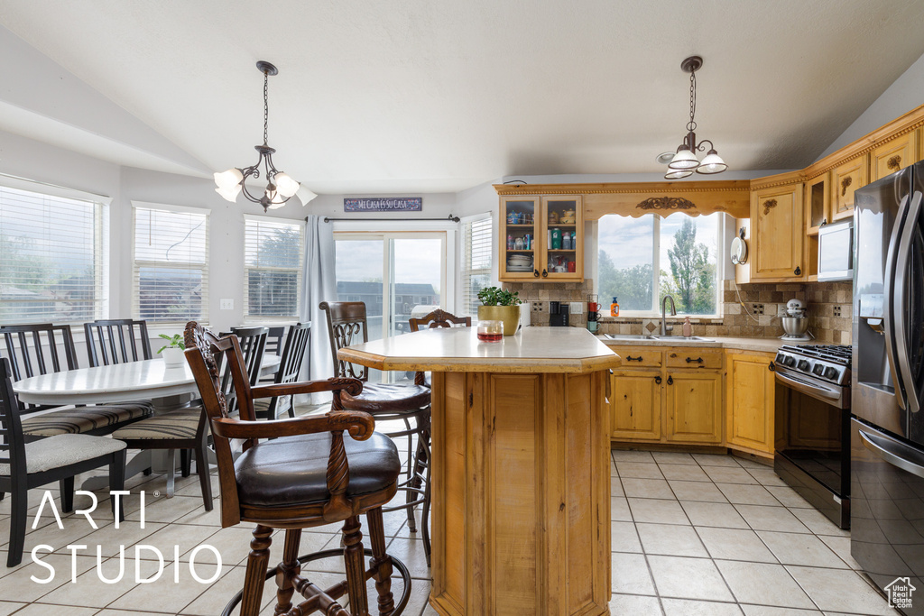 Kitchen featuring a sink, lofted ceiling, an inviting chandelier, light tile patterned floors, and appliances with stainless steel finishes