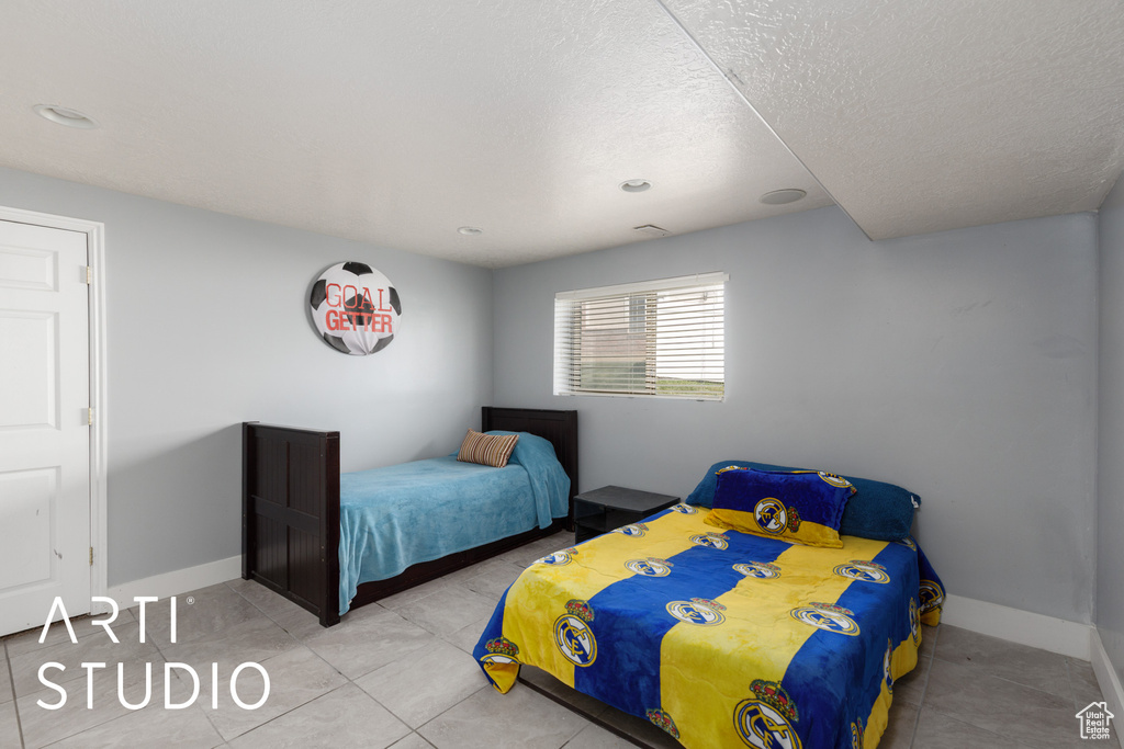Tiled bedroom with a textured ceiling and baseboards