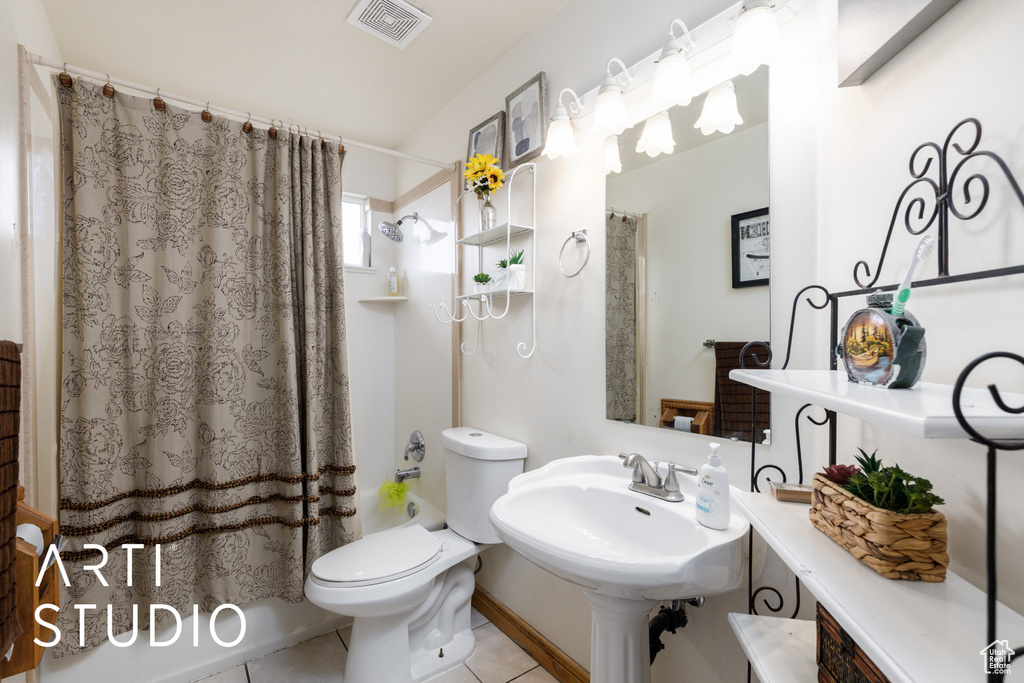 Bathroom featuring toilet, shower / bath combo, a sink, visible vents, and tile patterned flooring