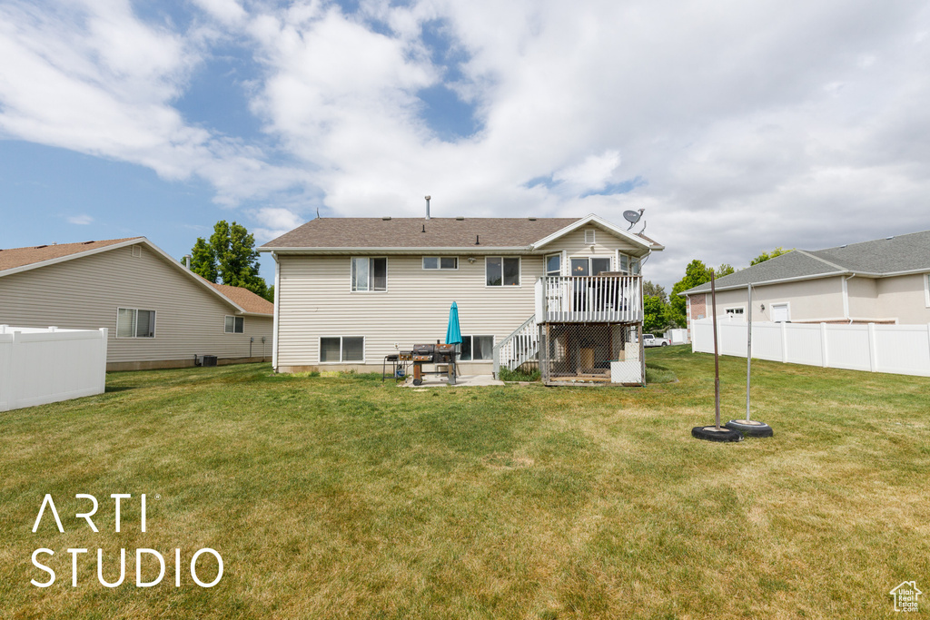 Back of house with a yard, fence, a wooden deck, and a patio
