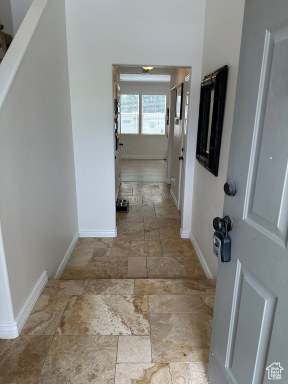 Hallway with baseboards and stone tile flooring
