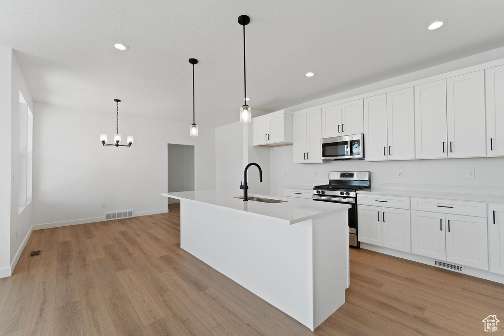 Kitchen with a notable chandelier, visible vents, a sink, light wood-style floors, and stainless steel appliances