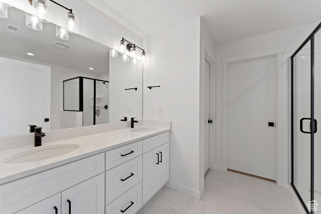 Full bath featuring a sink, double vanity, baseboards, and a shower stall