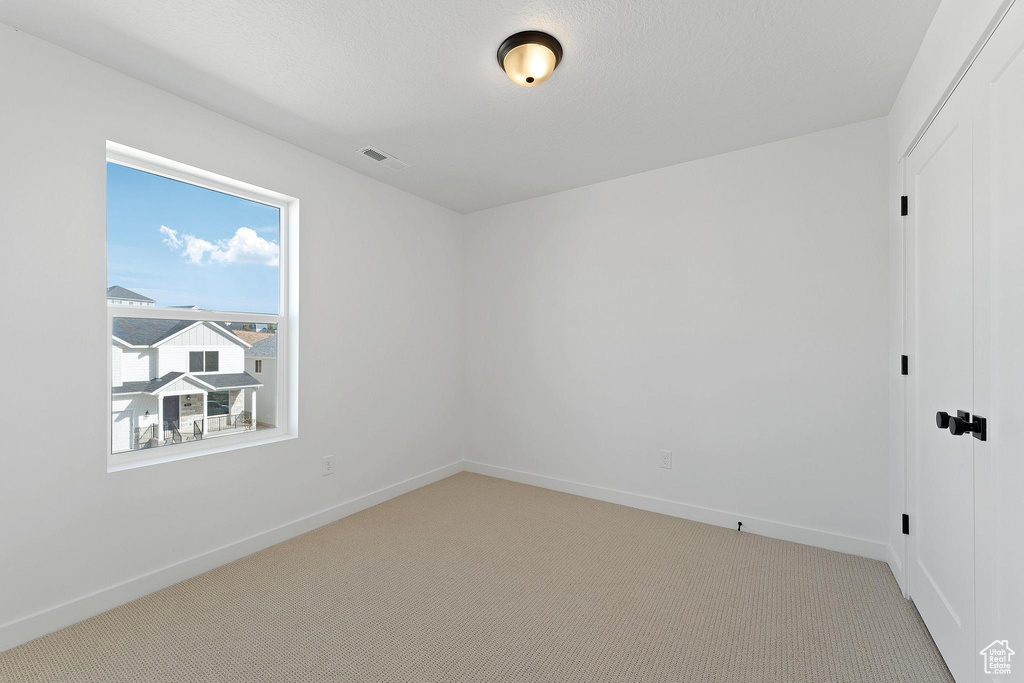 Spare room with baseboards, light carpet, and visible vents