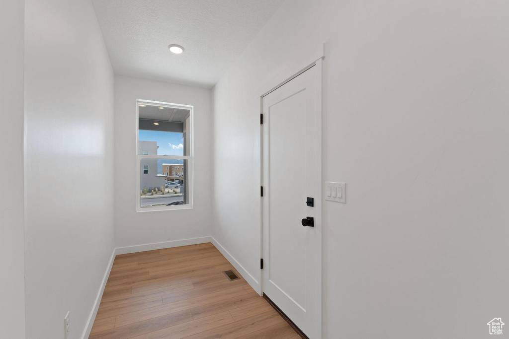 Hall featuring light wood-style flooring, baseboards, and visible vents