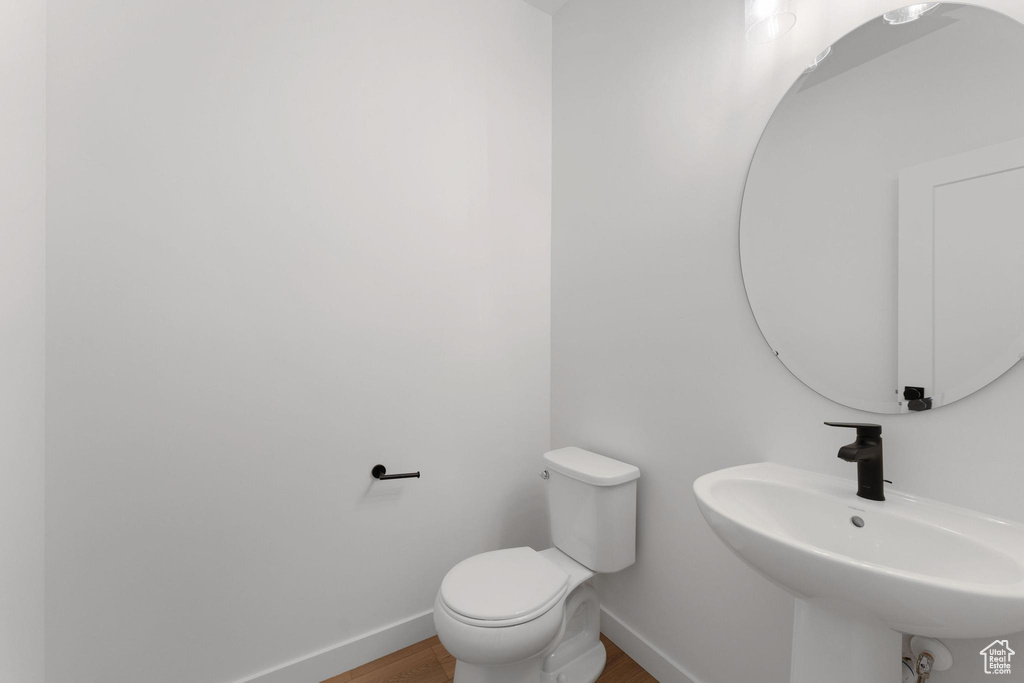 Bathroom featuring a sink, toilet, baseboards, and wood finished floors