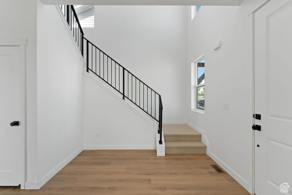 Foyer entrance featuring stairway, baseboards, visible vents, and light wood-style floors