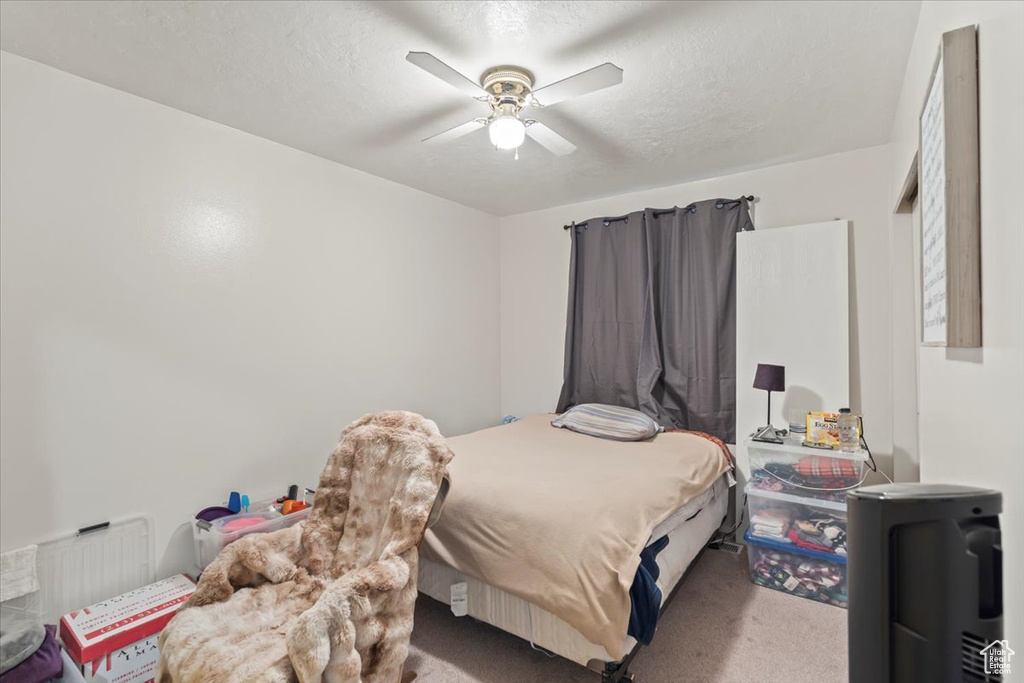 Bedroom featuring a ceiling fan, a textured ceiling, and carpet floors