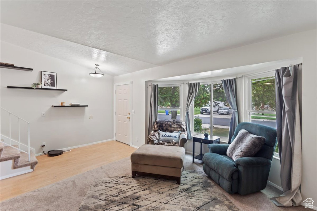 Living area with a textured ceiling, stairs, baseboards, and wood finished floors