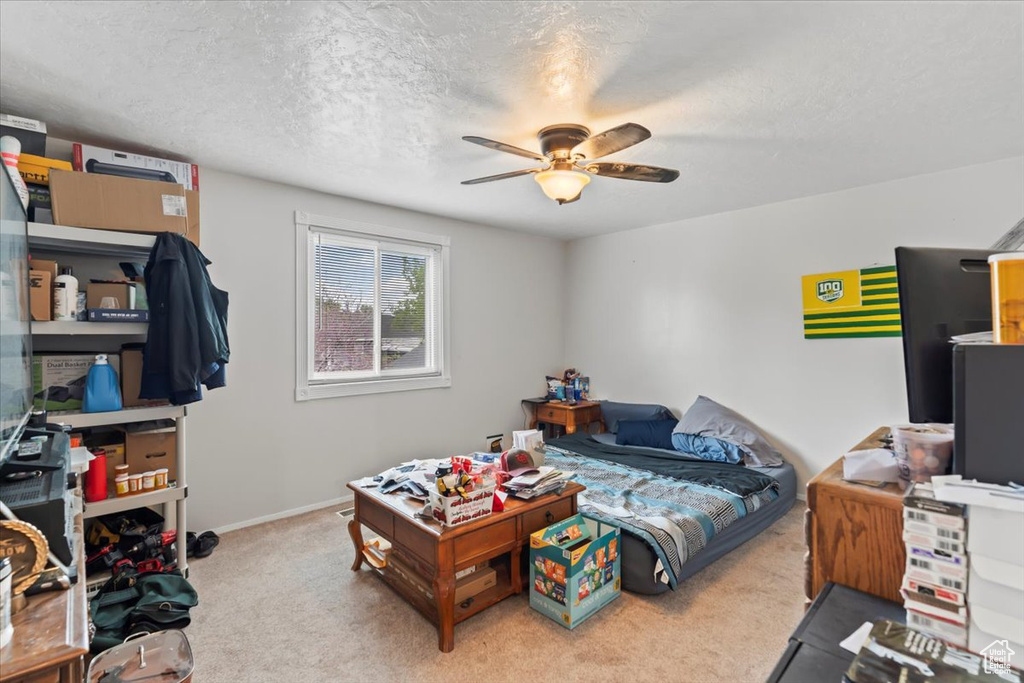 Carpeted bedroom featuring a textured ceiling and a ceiling fan