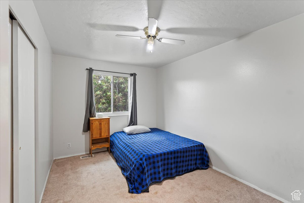 Carpeted bedroom with ceiling fan, a closet, and baseboards