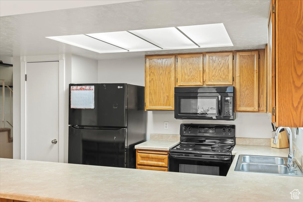 Kitchen with a sink, light countertops, and black appliances