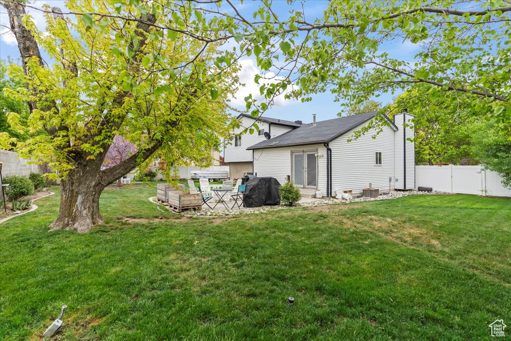 Back of property with a patio area, a chimney, a lawn, and a fenced backyard