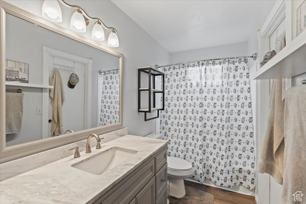Bathroom with a shower with curtain, vanity, toilet, and wood finished floors