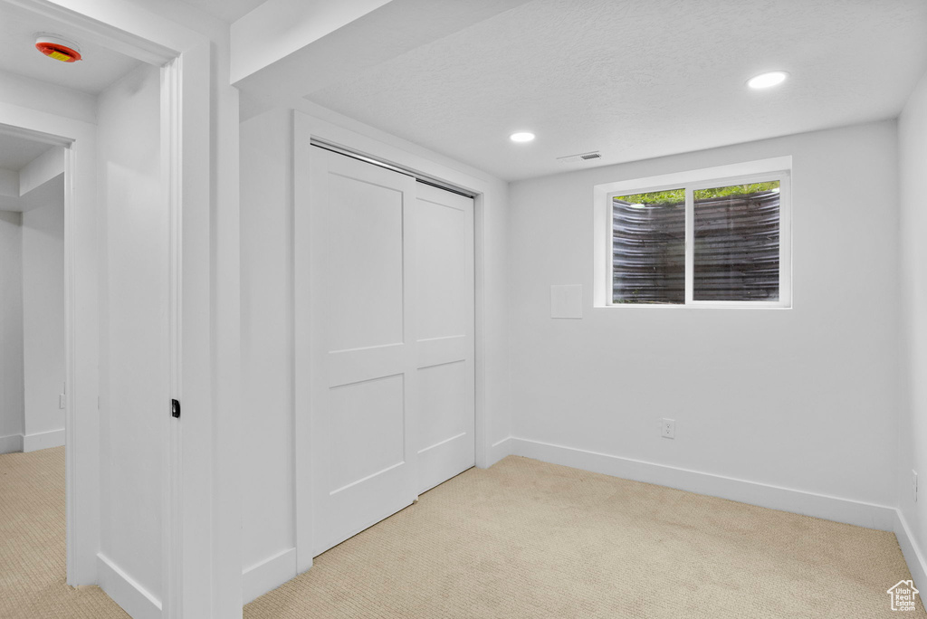 Unfurnished bedroom with baseboards and light carpet