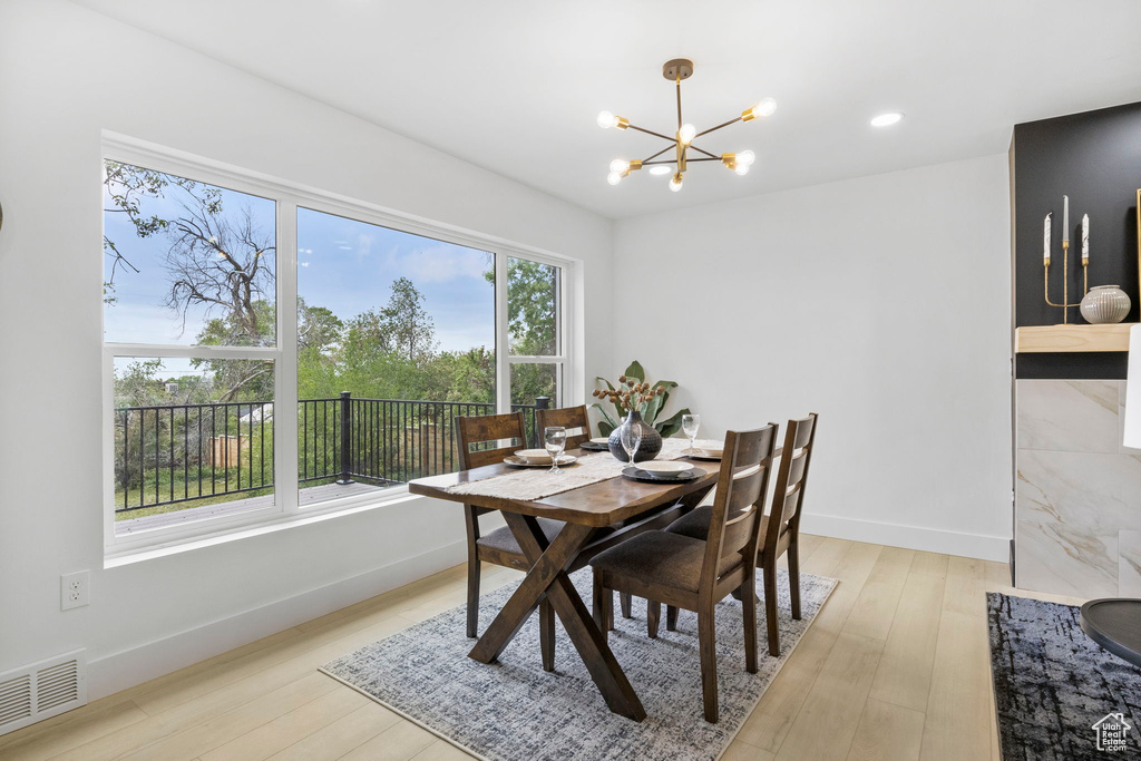 Dining room with an inviting chandelier, light wood-type flooring, visible vents, and baseboards