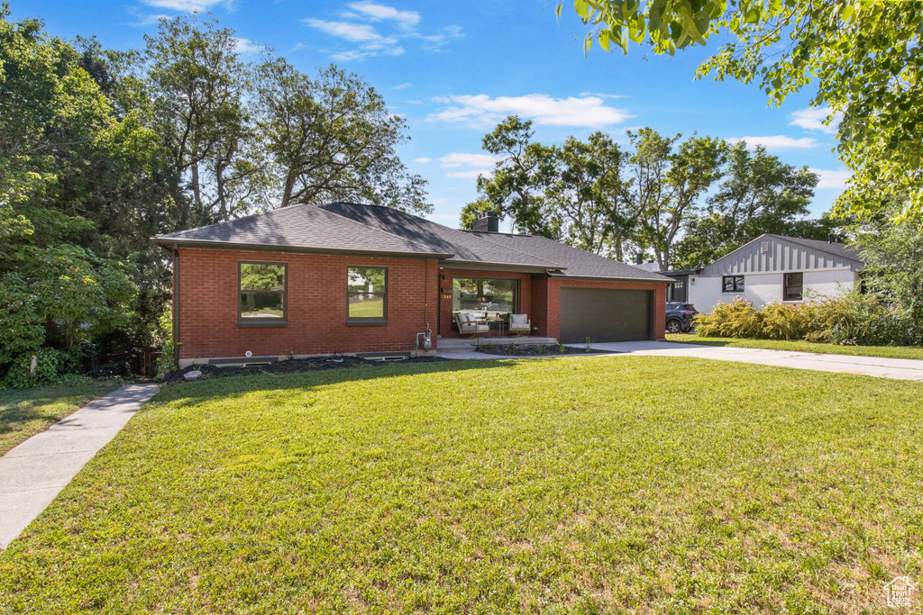 View of front of house with brick siding, concrete driveway, a front yard, and a garage