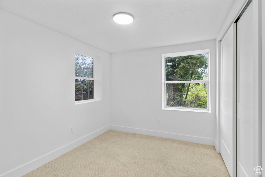 Spare room featuring light colored carpet, baseboards, and a healthy amount of sunlight