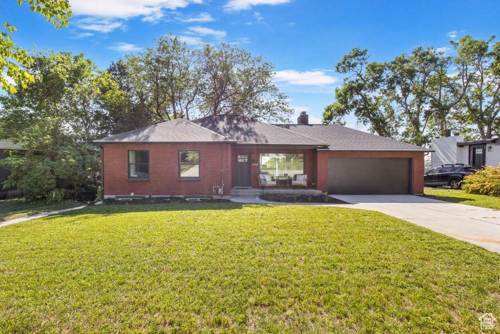 Single story home with brick siding, driveway, a garage, a front lawn, and roof with shingles
