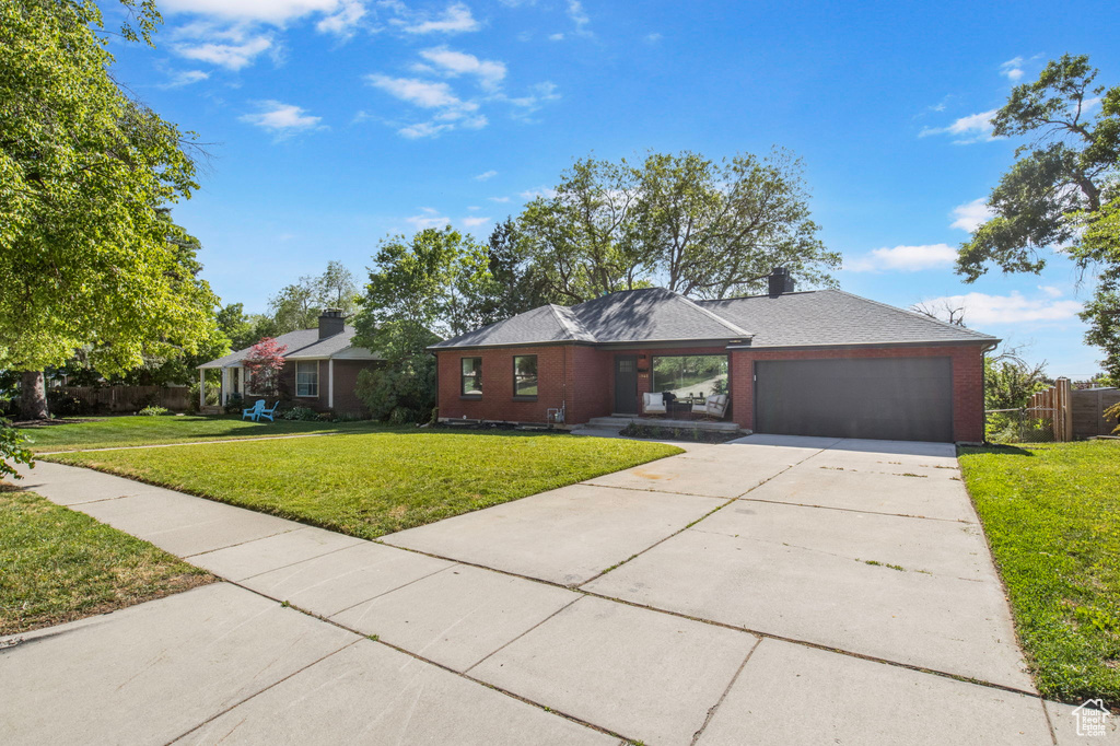 View of front of home with an attached garage, driveway, brick siding, and covered porch
