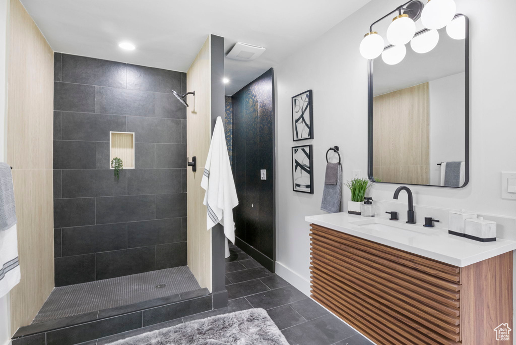 Full bath with baseboards, tile patterned flooring, vanity, and tiled shower