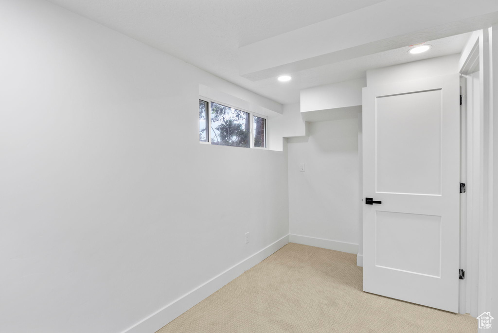 Below grade area with light carpet, baseboards, and recessed lighting