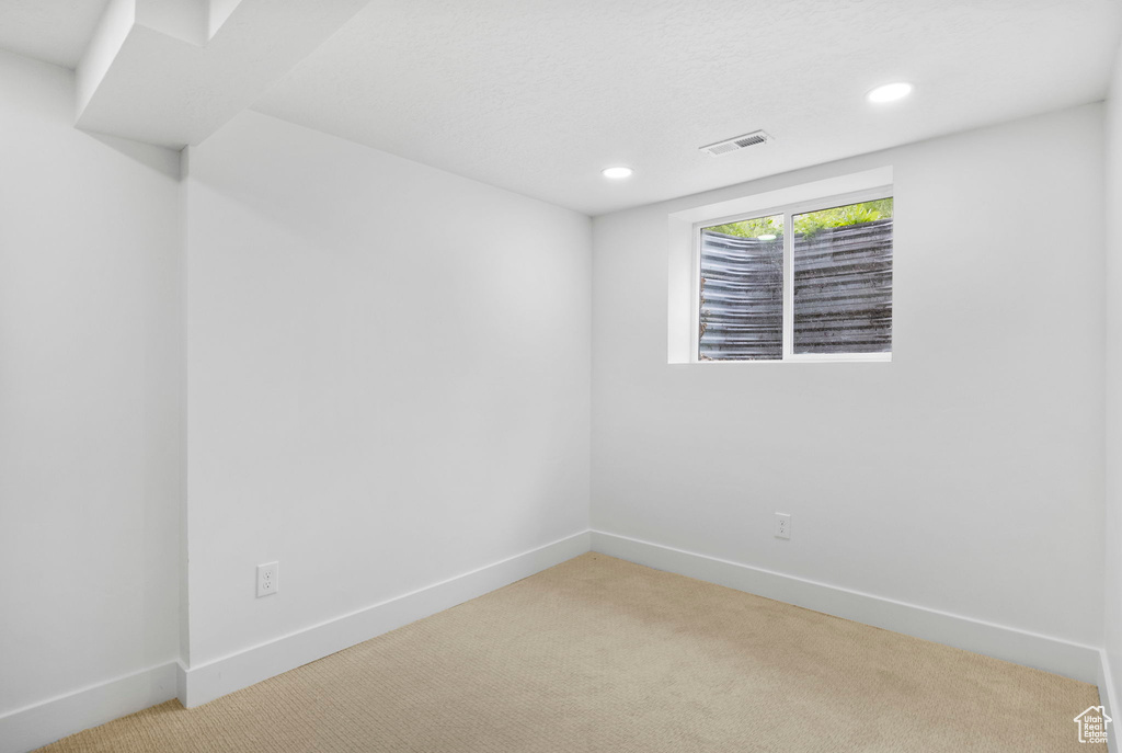 Empty room with baseboards, visible vents, recessed lighting, and light colored carpet