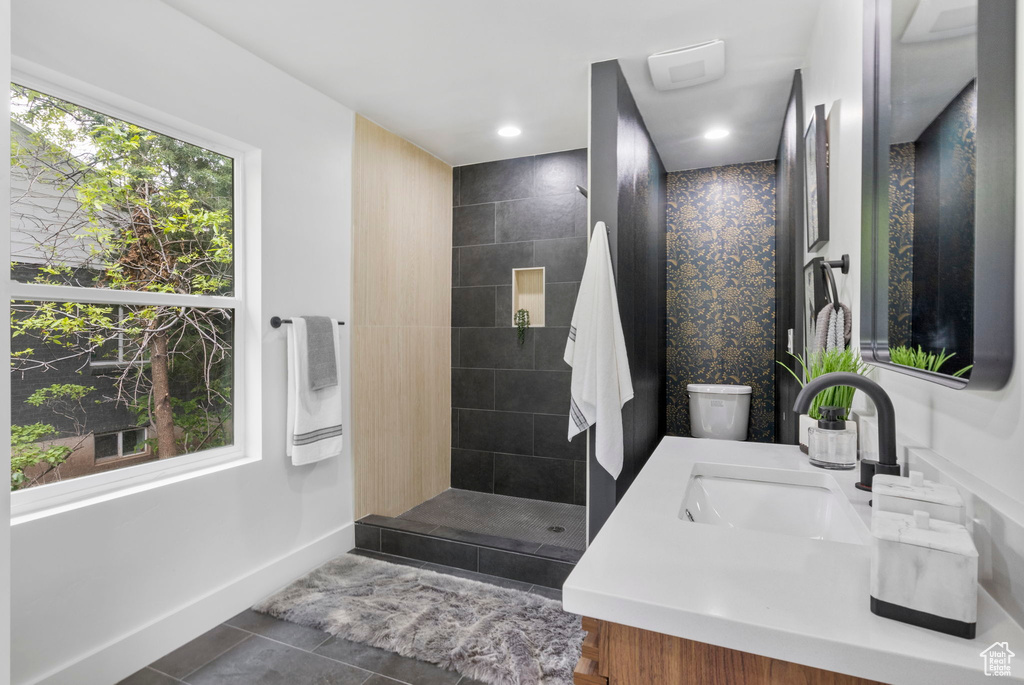Bathroom with vanity, a walk in shower, baseboards, and tile patterned floors