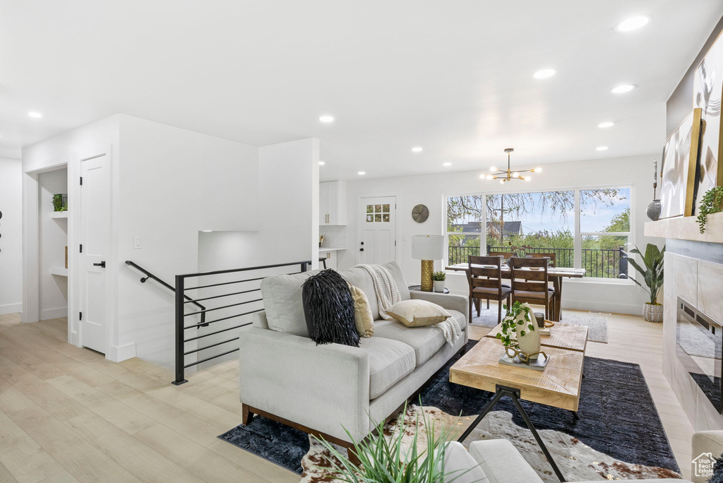 Living area with recessed lighting, baseboards, an inviting chandelier, a tile fireplace, and light wood-type flooring