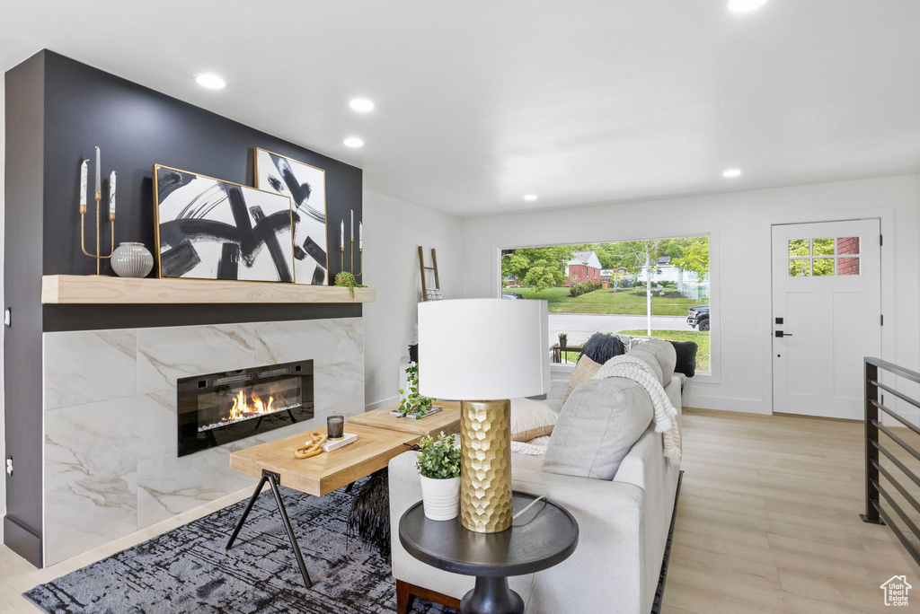 Living room featuring light wood-type flooring, a high end fireplace, and recessed lighting