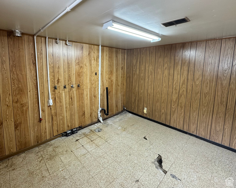 Finished basement with light floors, wood walls, and visible vents