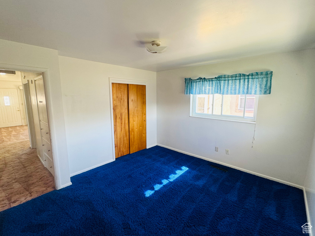 Unfurnished bedroom with carpet flooring, a closet, and baseboards
