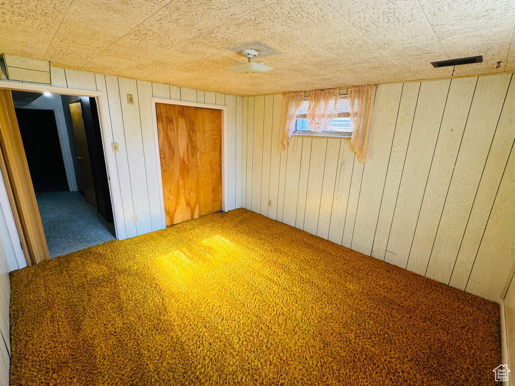Unfurnished bedroom featuring wood walls, a closet, carpet, and visible vents