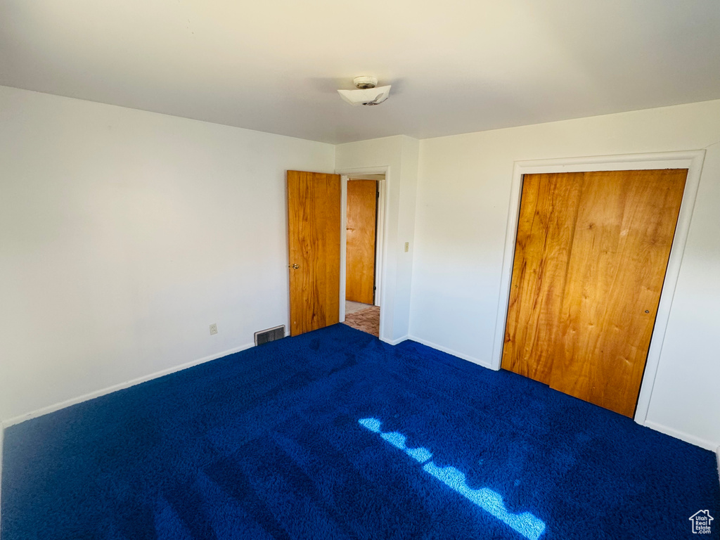 Unfurnished bedroom featuring carpet flooring, baseboards, a closet, and visible vents