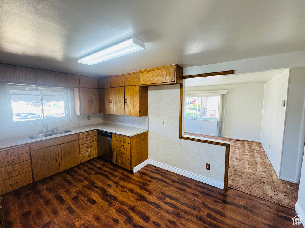 Kitchen with a sink, dark wood finished floors, stainless steel dishwasher, plenty of natural light, and light countertops