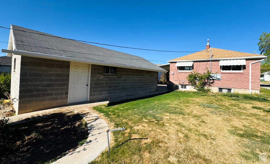 Back of property featuring roof with shingles and a lawn