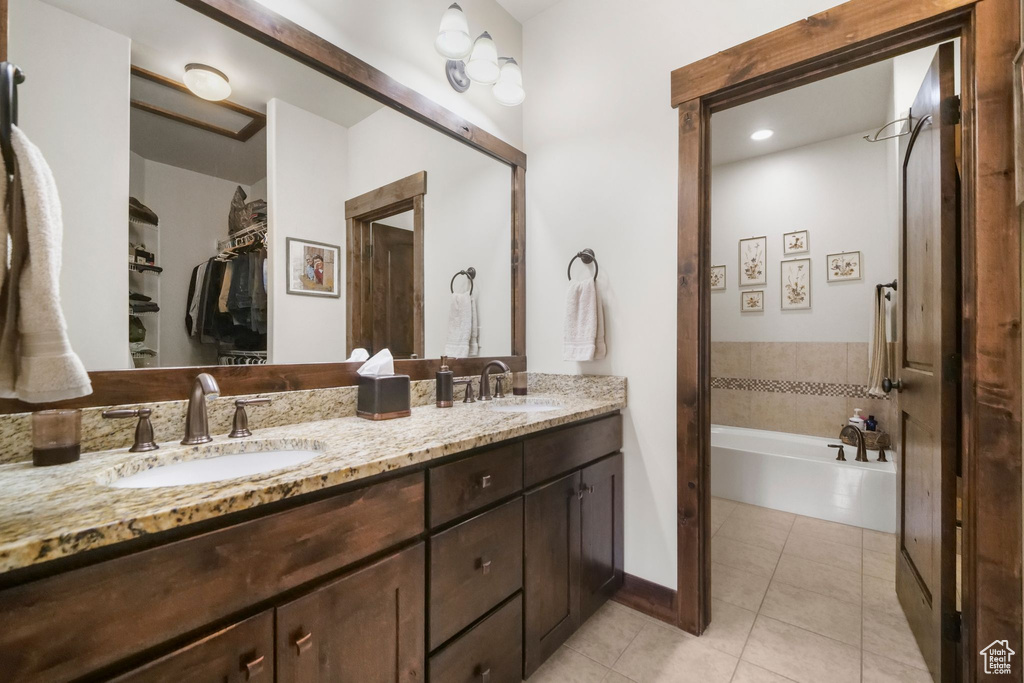 Bathroom with a bathing tub, tile patterned floors, double vanity, and a sink