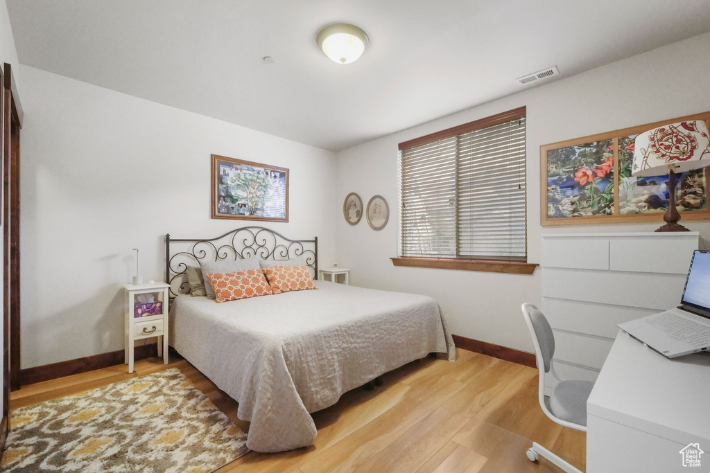 Bedroom featuring light wood finished floors, baseboards, and visible vents