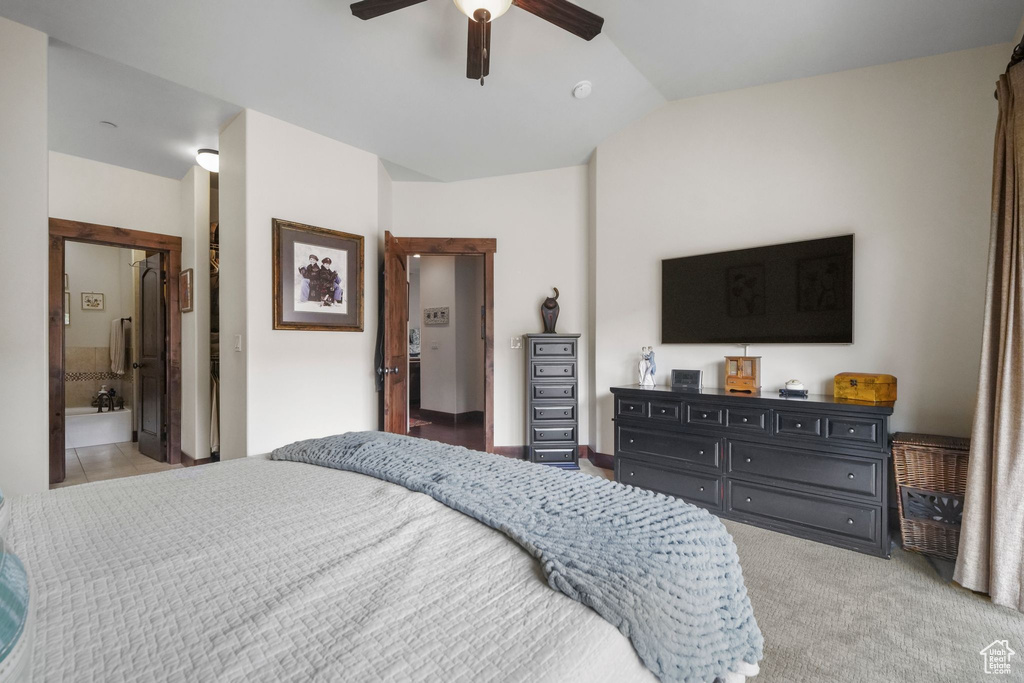 Bedroom with a ceiling fan, ensuite bathroom, carpet, and vaulted ceiling